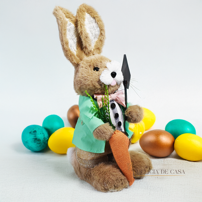 Coelho de pelúcia decorativo vestido com roupa social verde, segurando uma cenoura e uma enxada, ideal para decoração de Páscoa e ambientes rústicos.