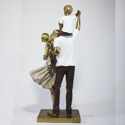 Escultura decorativa de família com pai, mãe, um filho e uma filha, confeccionada em resina com acabamento dourado, branco e marrom, medindo 29,5 x 14 x 8,5 cm.