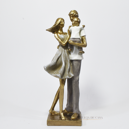 Estatueta decorativa de um casal com filho no colo, feita em resina com acabamento dourado e tons suaves, simbolizando amor e união familiar.