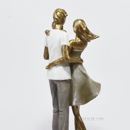 Estatueta decorativa de um casal com filho no colo, feita em resina com acabamento dourado e tons suaves, simbolizando amor e união familiar.