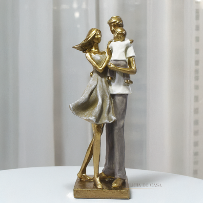 Estatueta decorativa de um casal com filho no colo, feita em resina com acabamento dourado e tons suaves, simbolizando amor e união familiar.