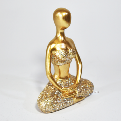 Trio de estátuas douradas com glitter representando posturas de ioga, ideal para decoração zen e ambientes de meditação.