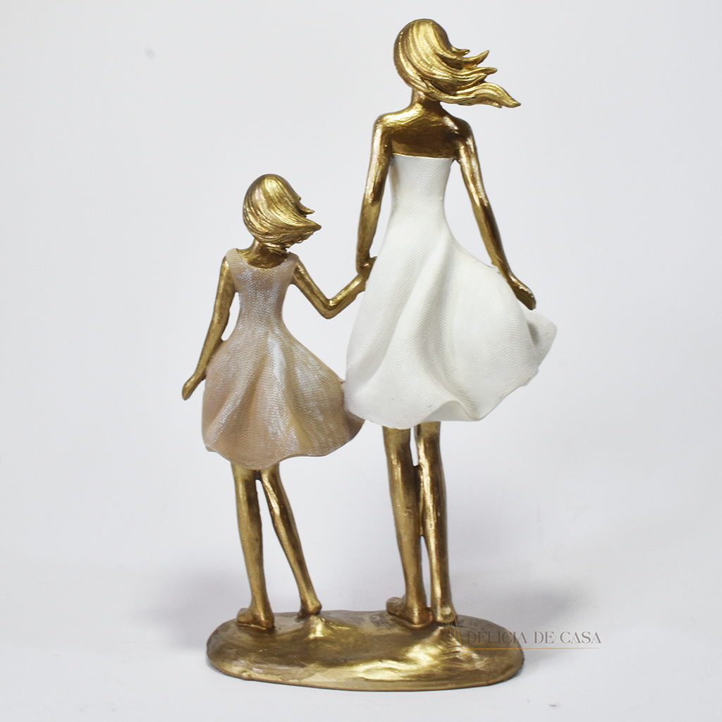 Estatueta decorativa em resina representando mãe e filha de mãos dadas, com acabamento dourado e vestidos em tons suaves. Peça elegante para simbolizar amor e conexão familiar na decoração.