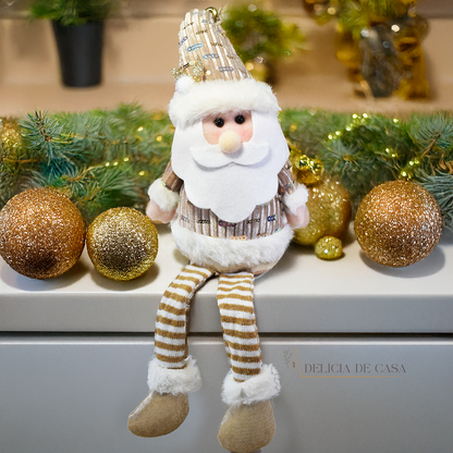 Boneco decorativo de Papai Noel sentado com pernas longas, roupas douradas e barba branca, ideal para decoração natalina em mesas e prateleiras.