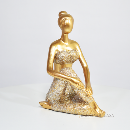 Escultura de mulher em posição de yoga com acabamento dourado e glitter. Uma peça decorativa que une elegância e serenidade, perfeita para decorar ou presentear.