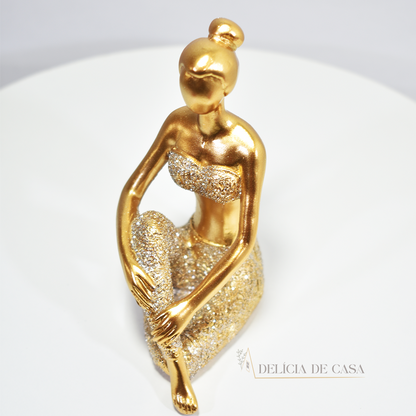 Escultura de mulher em posição de yoga com acabamento dourado e glitter. Uma peça decorativa que une elegância e serenidade, perfeita para decorar ou presentear.